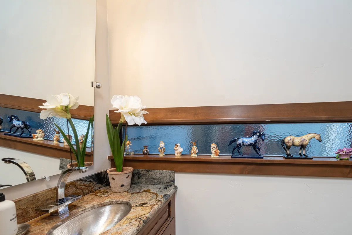 Shows a charming vanity area with decorative figurines, fresh flowers, and a sink, set in a tranquil, thoughtfully decorated space. The mood is peaceful, suggesting moments of quiet grooming and relaxation.