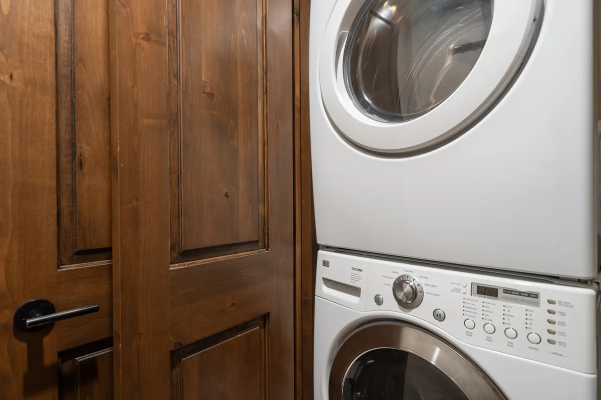 This image features a well-lit laundry facility with modern washer and dryer units, a sturdy wooden door, and organized laundry supplies, evoking a sense of convenience and practicality.